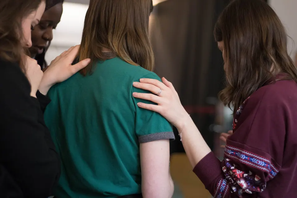 Two women praying for each other at a monthly gathering